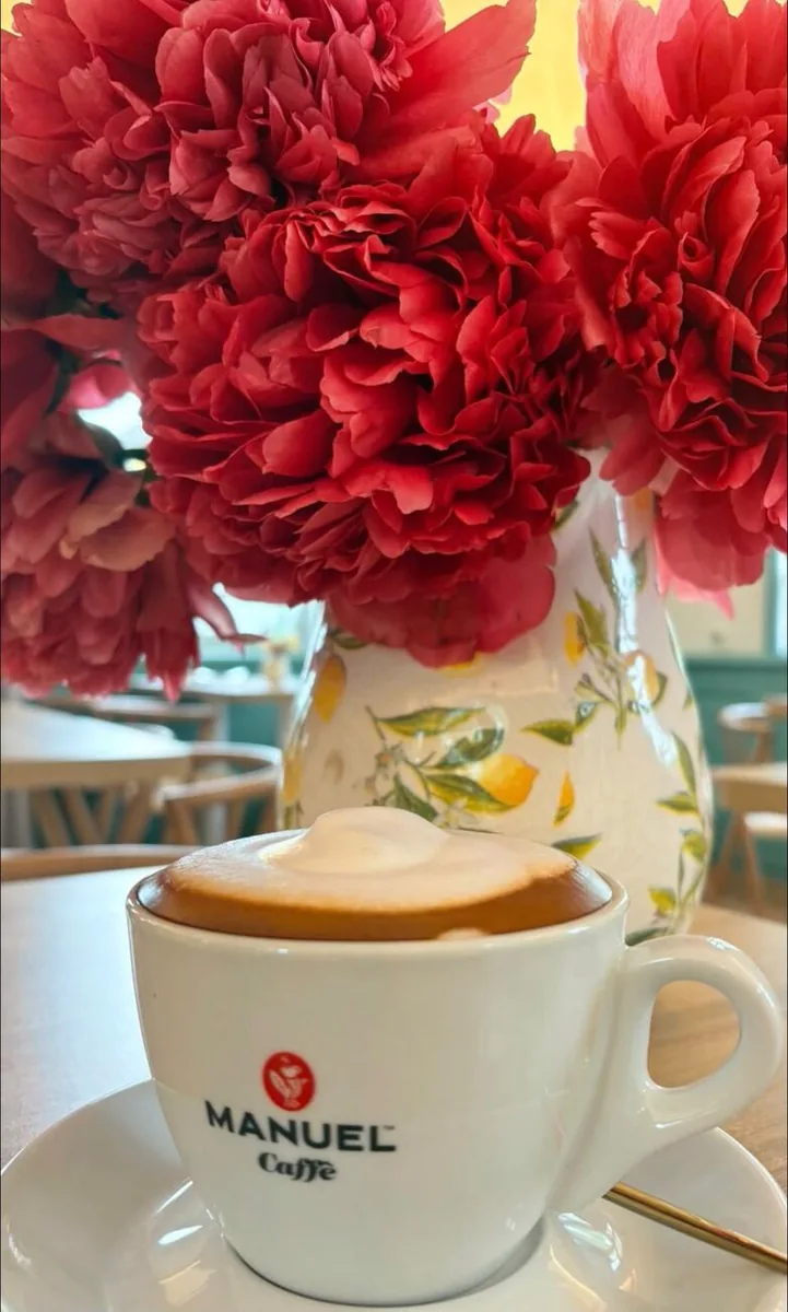Cappuccino mit Pfingstrosen auf einem Tisch im Schlossgarten Café